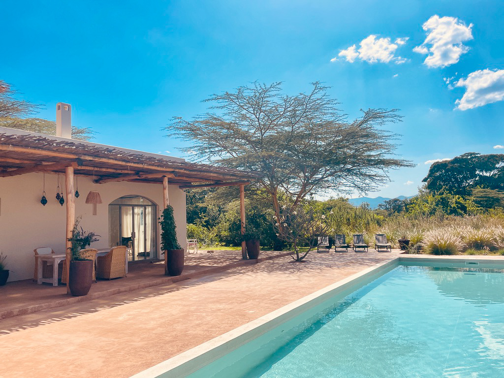 Pool framed by acacia trees with Ngong Hills in the distance