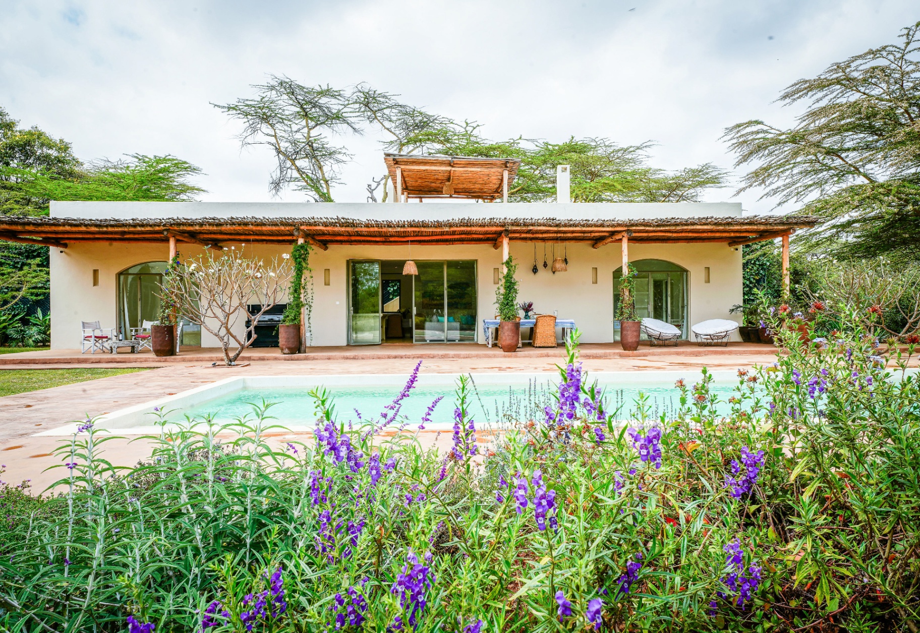 Pool House facade with pergola veranda and pool in the foreground