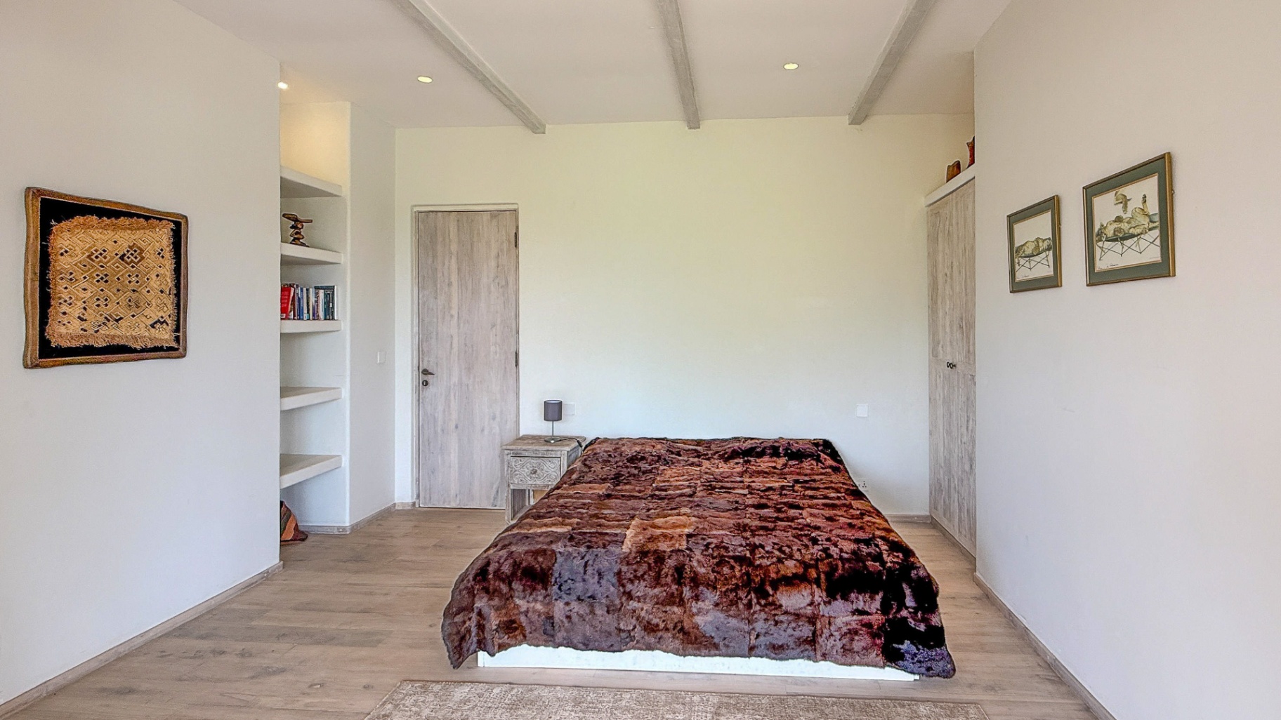 Simple bedroom with warm brown throw and built-in shelving