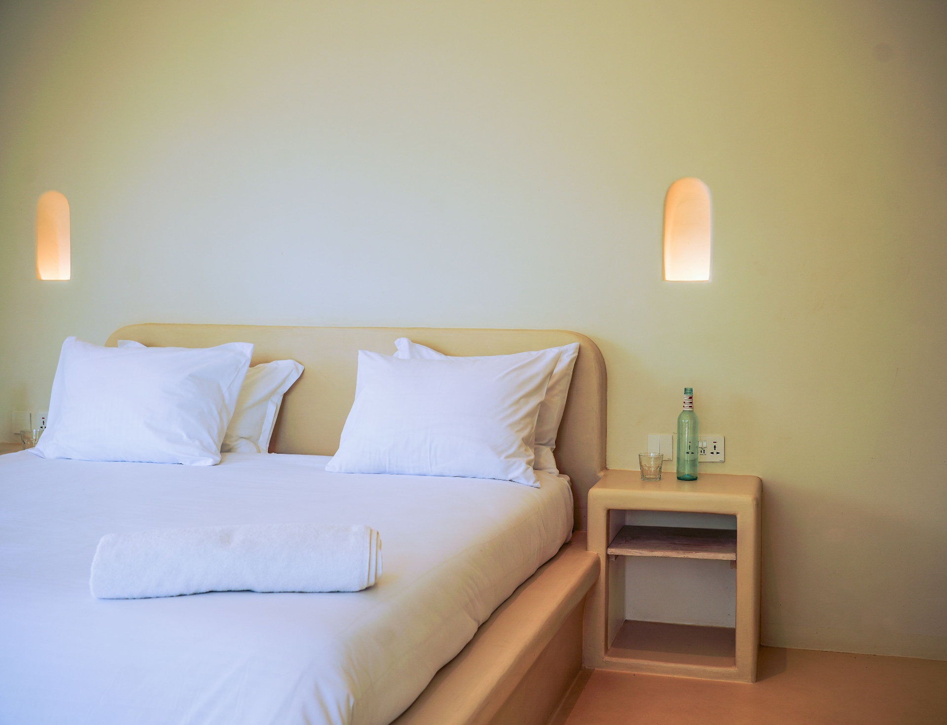 Bedroom with king bed, plaster headboard and arched wall lights